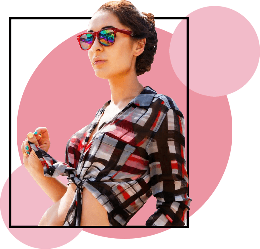 A woman in sunglasses and plaid shirt holding onto a cell phone.