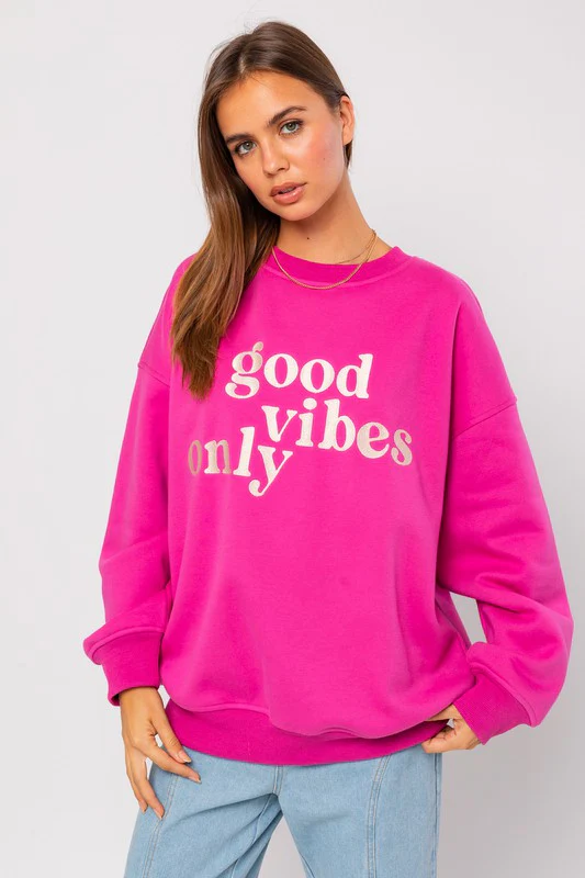 Woman wearing pink good vibes only sweatshirt.