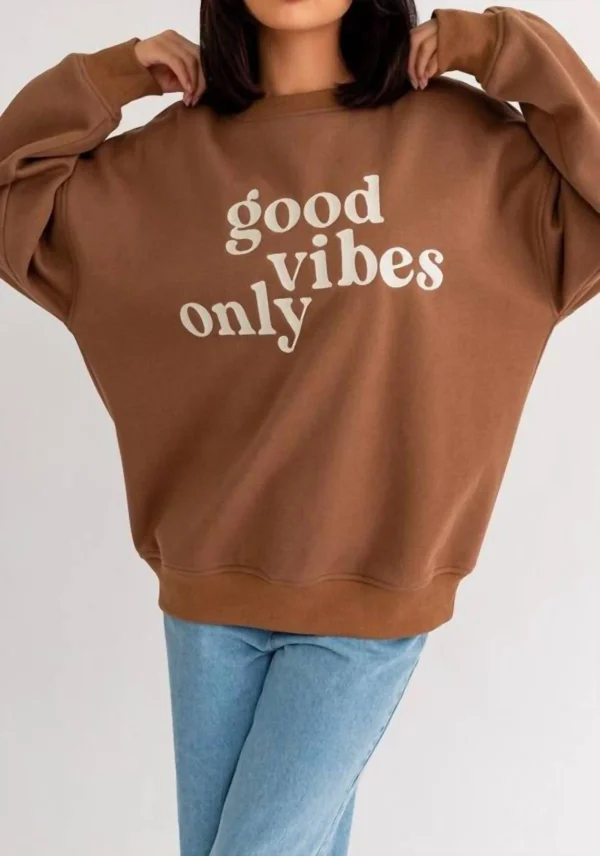 Brown sweatshirt with "good vibes only" slogan.