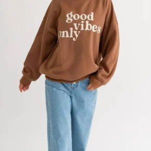 Woman wearing a brown "good vibes only" sweatshirt.