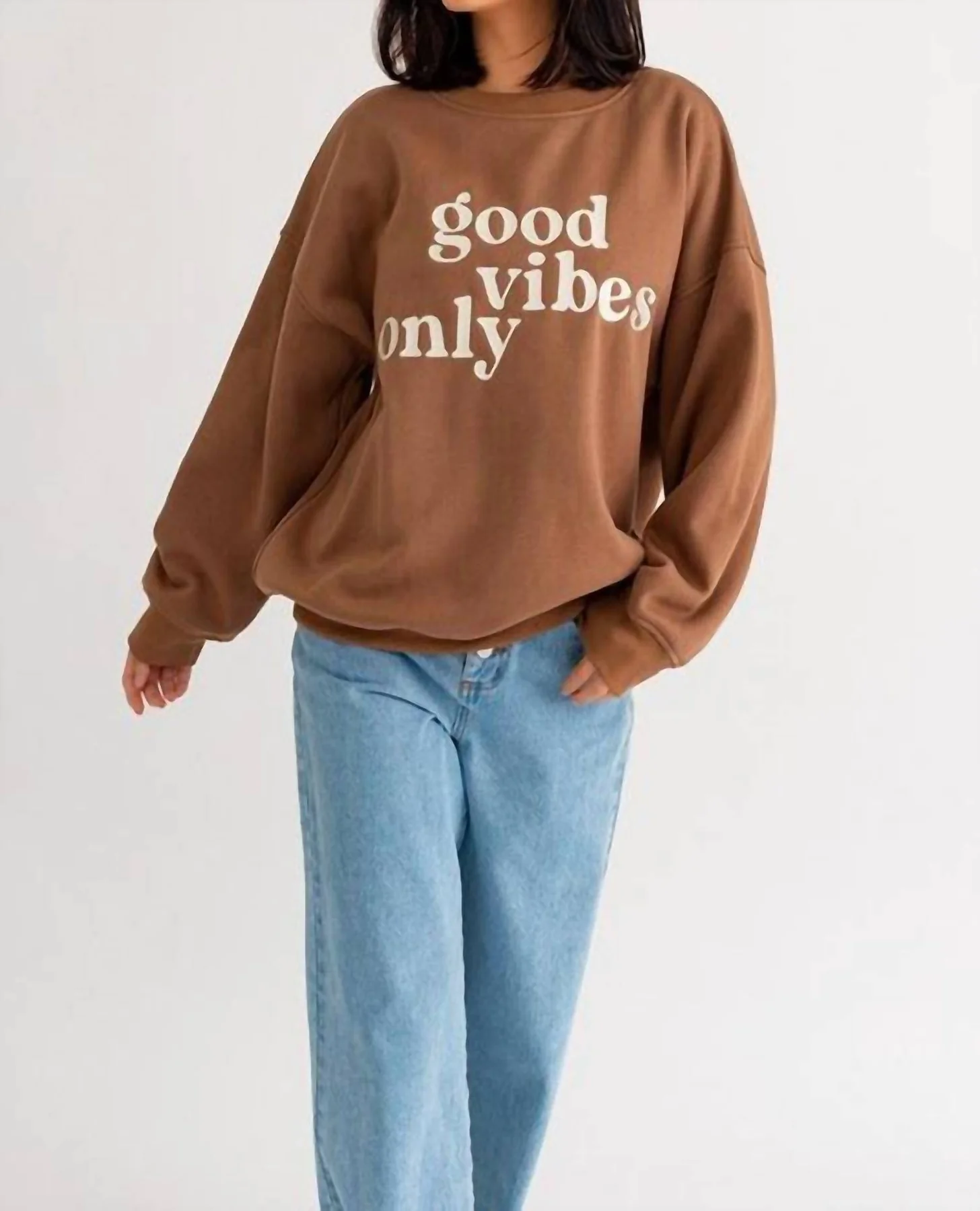 Woman wearing a brown "good vibes only" sweatshirt.