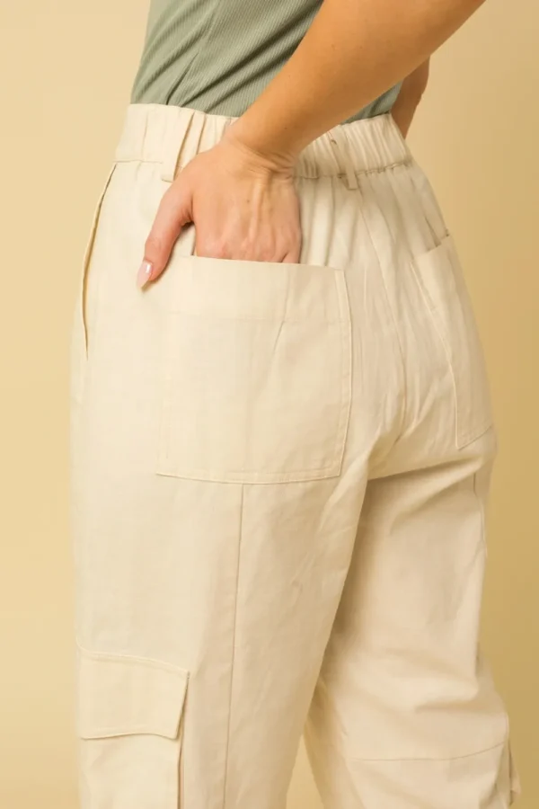 A person with their hand in the pocket of a pair of white pants.