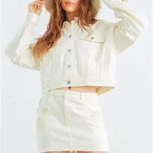 A woman in white jacket and skirt holding her hair.