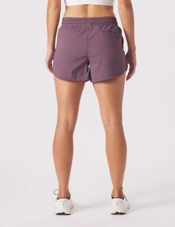 A woman wearing purple shorts and white sneakers.