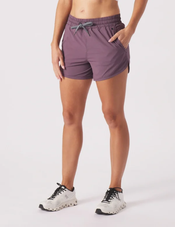 A woman wearing purple shorts and black sneakers.