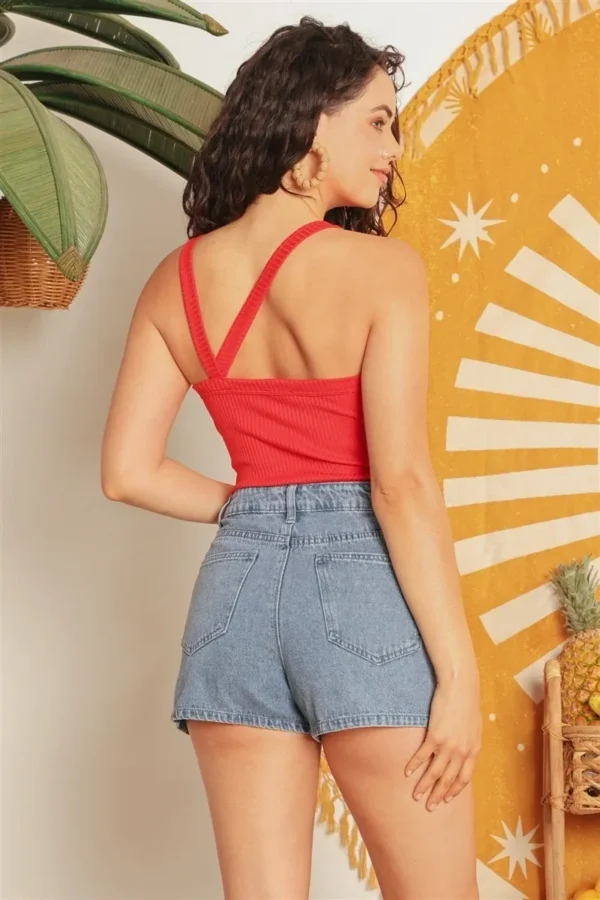 A woman wearing high waisted shorts and red top.