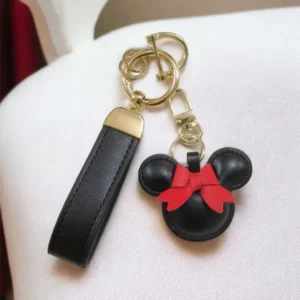 A mickey mouse keychain and key chain on top of a chair.