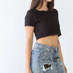 A woman wearing a black crop top and denim skirt.