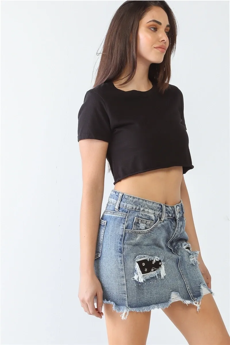 A woman wearing a black crop top and denim skirt.