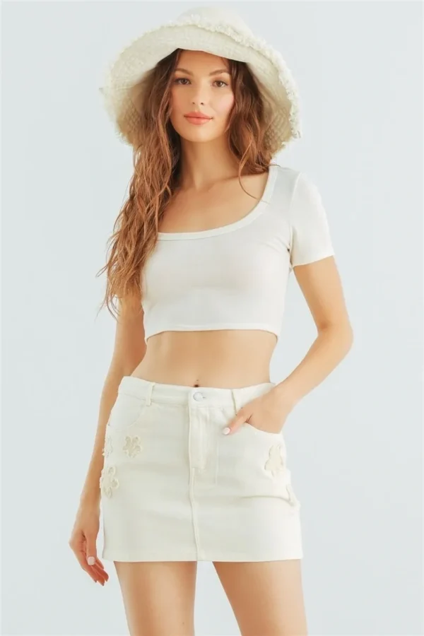 A woman wearing white shorts and a crop top.