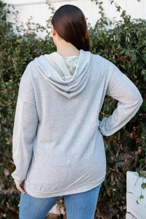 A woman wearing a gray hoodie and jeans.