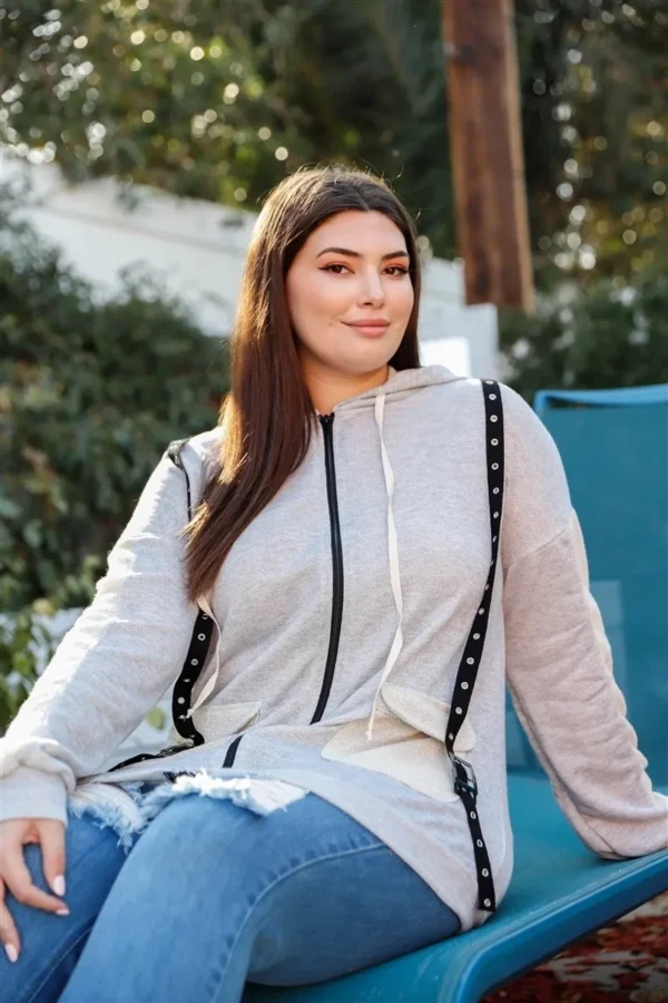 A woman sitting on the ground wearing jeans and a jacket.