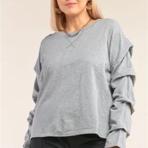 A woman wearing a gray sweatshirt with ruffles on the sleeves.