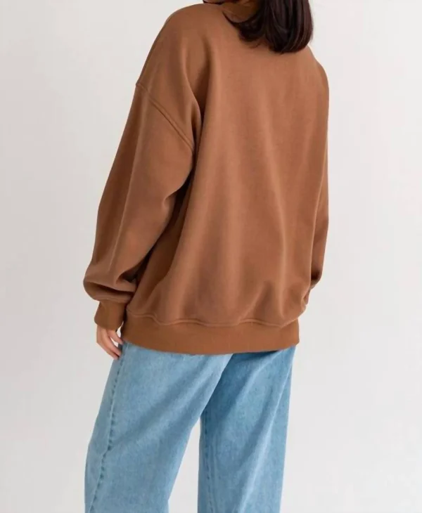 Woman wearing a brown sweatshirt and jeans.