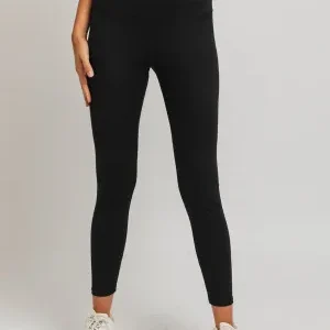 A woman wearing black leggings and white sneakers.