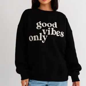 A woman wearing a black sweatshirt with the words " good vibes only ".