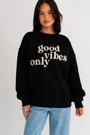 A woman wearing a black sweatshirt with the words " good vibes only ".