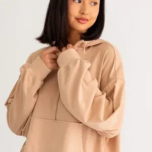 A woman in tan hoodie posing for the camera.