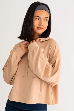 A woman in tan hoodie posing for the camera.