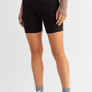 Woman wearing black biker shorts and white shoes.