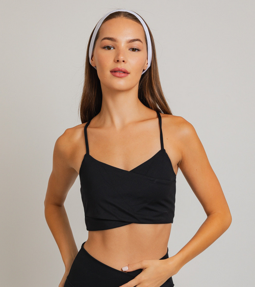 Woman in black sports bra with white headband.